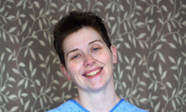 A woman in a hospital gown smiling